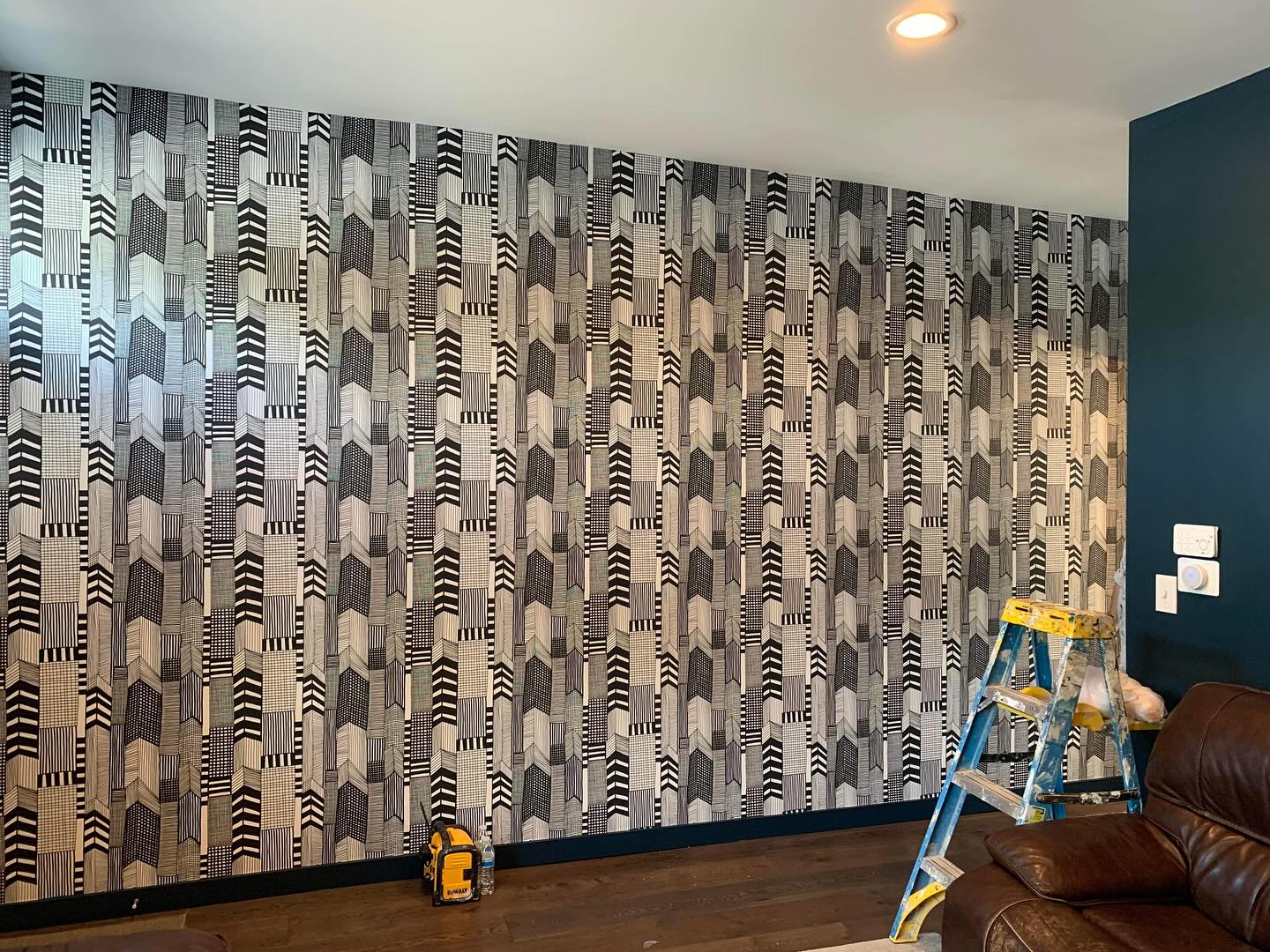 Professional wallpaper installer working on a patterned feature wall